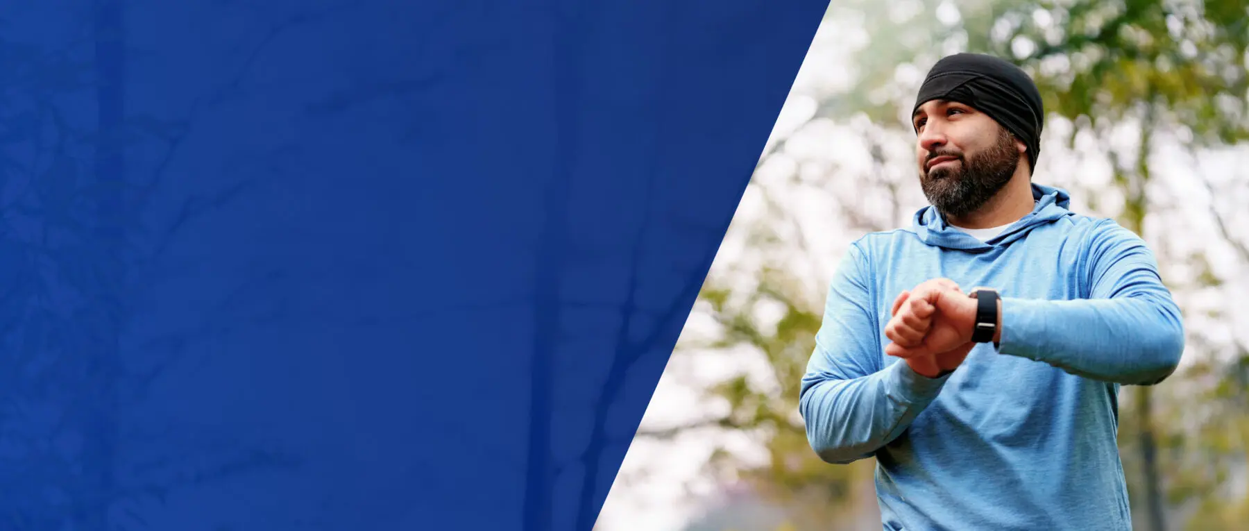 Jogger holding up his watch and looking to the left.