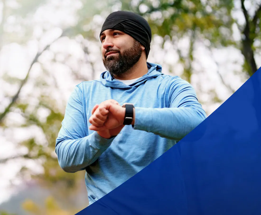 Jogger holding up his watch and looking to the left.