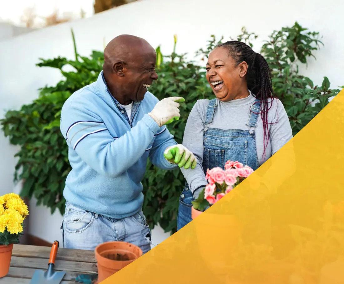 Senior couple planting flowers in a pot together.