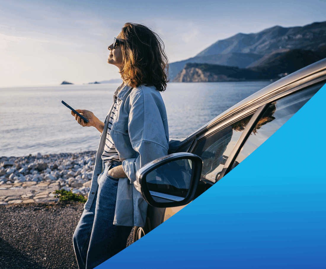 Woman holding a cell phone and leaning against a car.